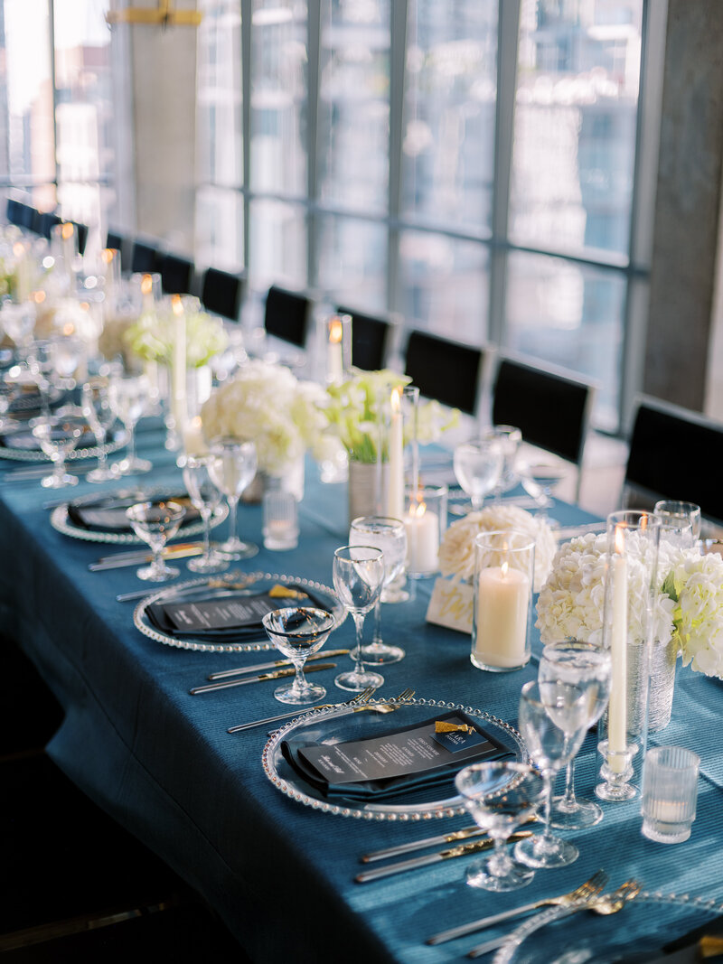Table with black chairs and floralscape with candles.