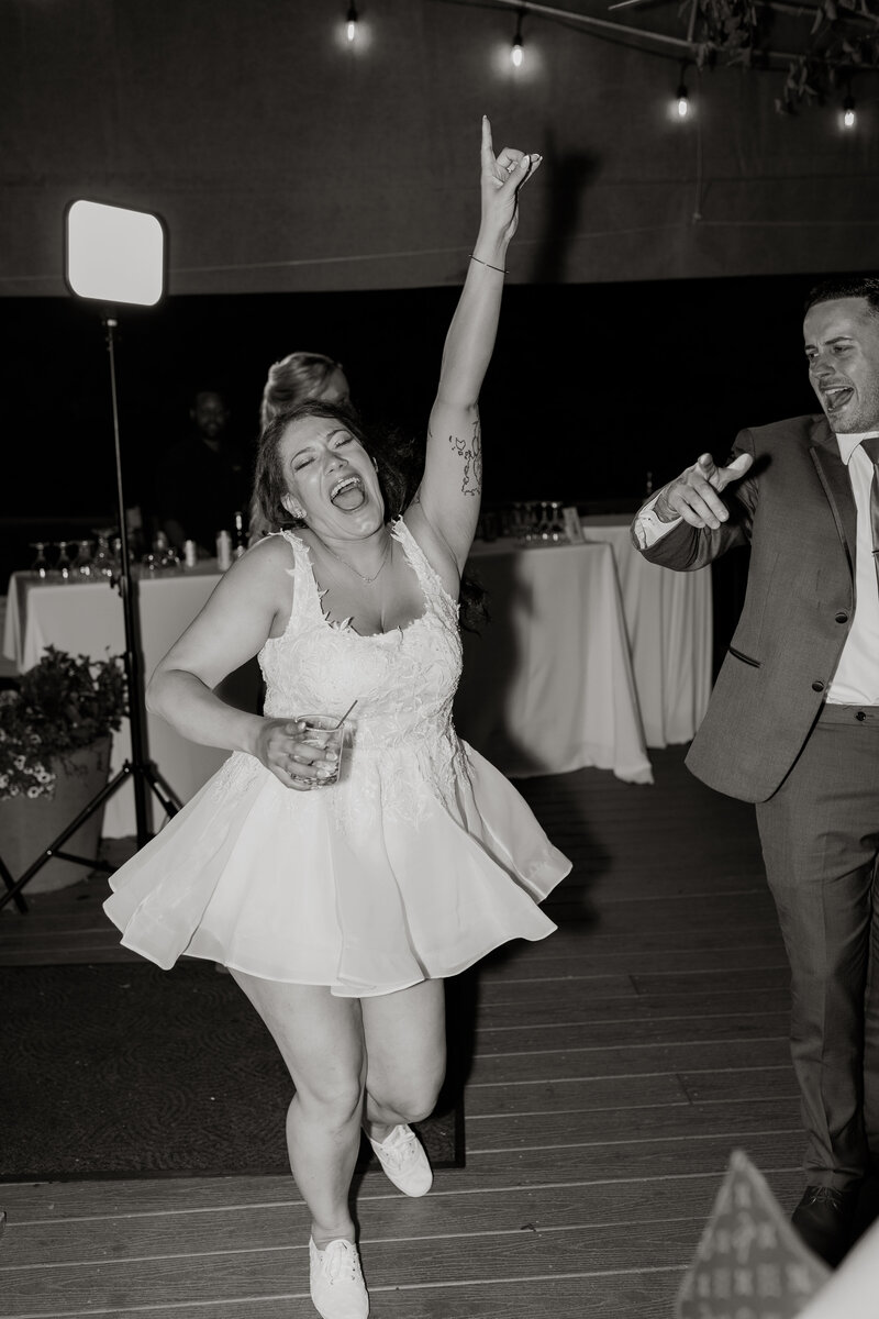 Black and white image of bride in short dress dancing on a dance floor