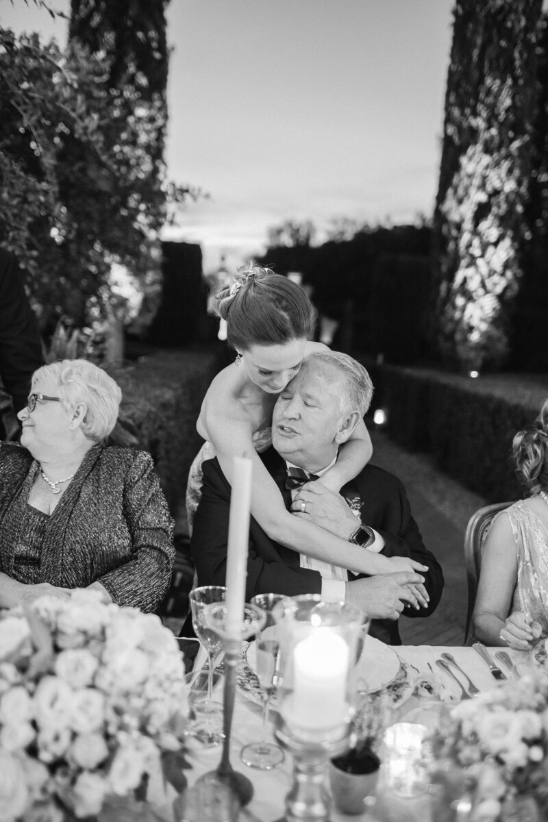 a luxury bride hugs her dad from behind at her wedding reception at La Piazzole in Florence Italy wedding villa photographed by top wedding photographer Dale Benfield Photographer