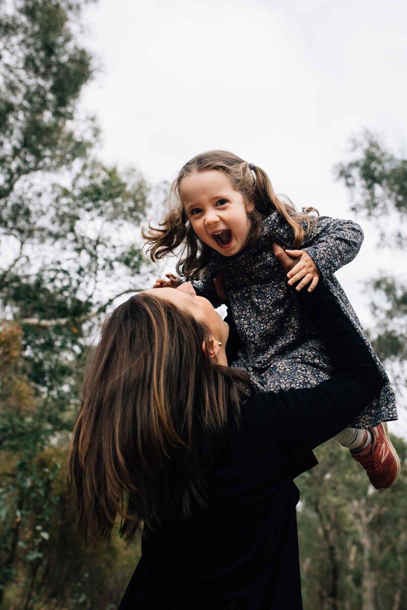 Happy daughter held up in air by her mother during outdoor family photoshoot Melbourne