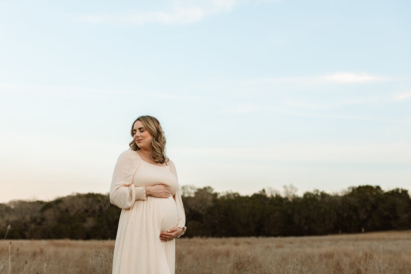 Pregnant woman and husband hugging her playfully from behind