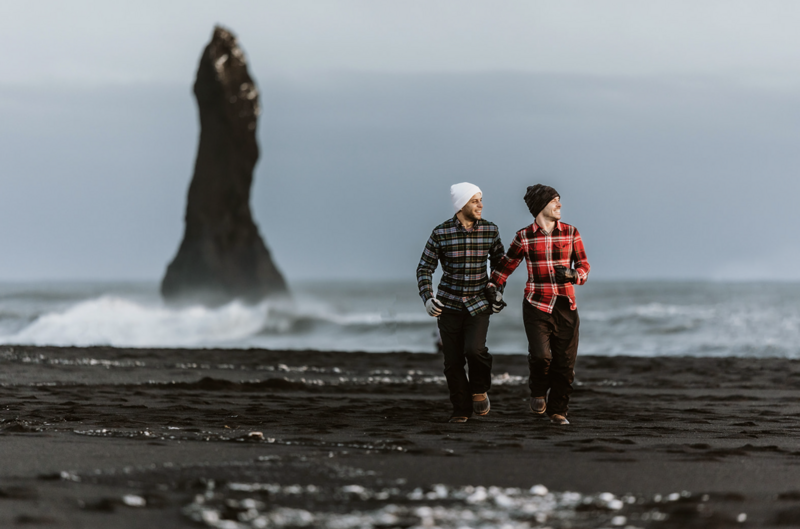 groom and groom are running on the black sand beach in iceland