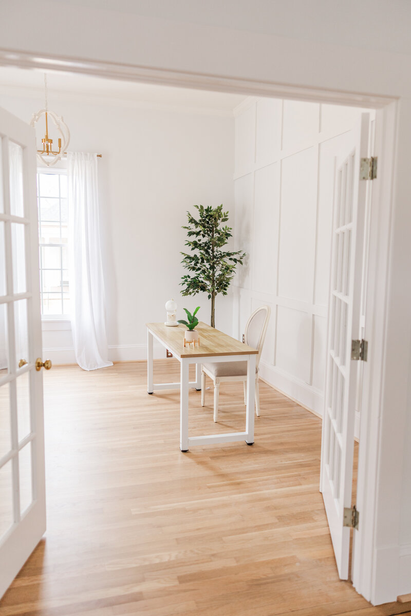 a room with French doors, a desk, and a plant