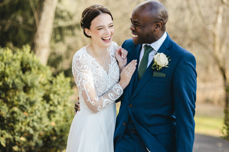 A newlywed couple with their arms around each other laughing 
