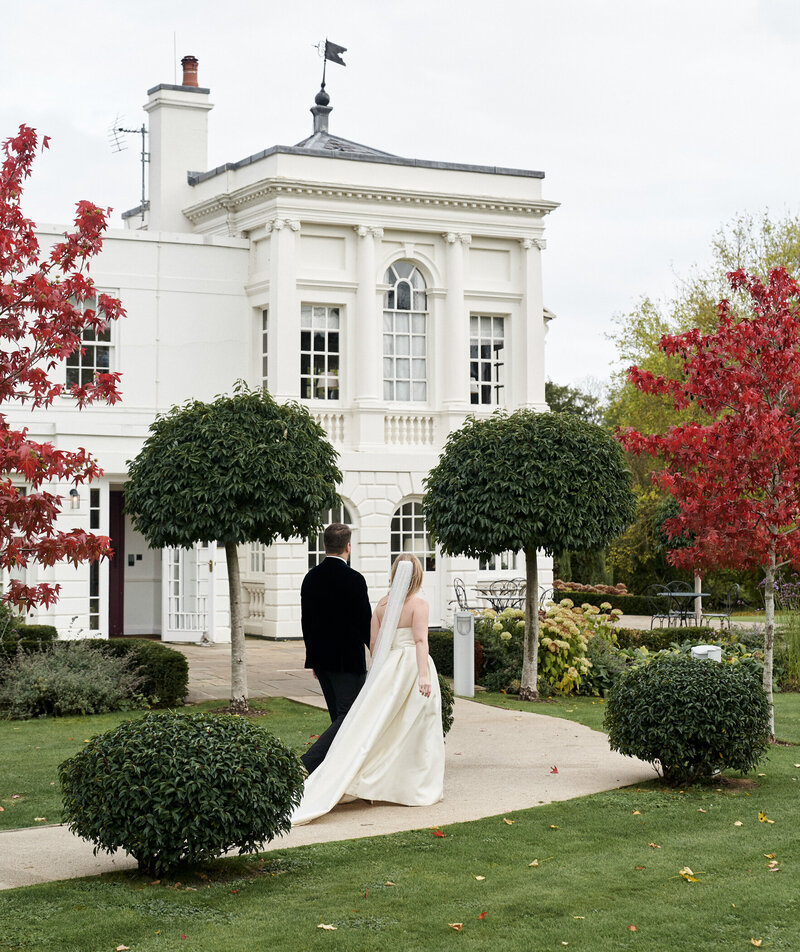 bride and groom walking away with building in the background