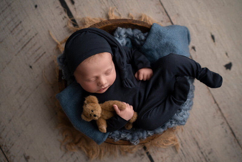 newborn baby boy with teddy bear in a bowl