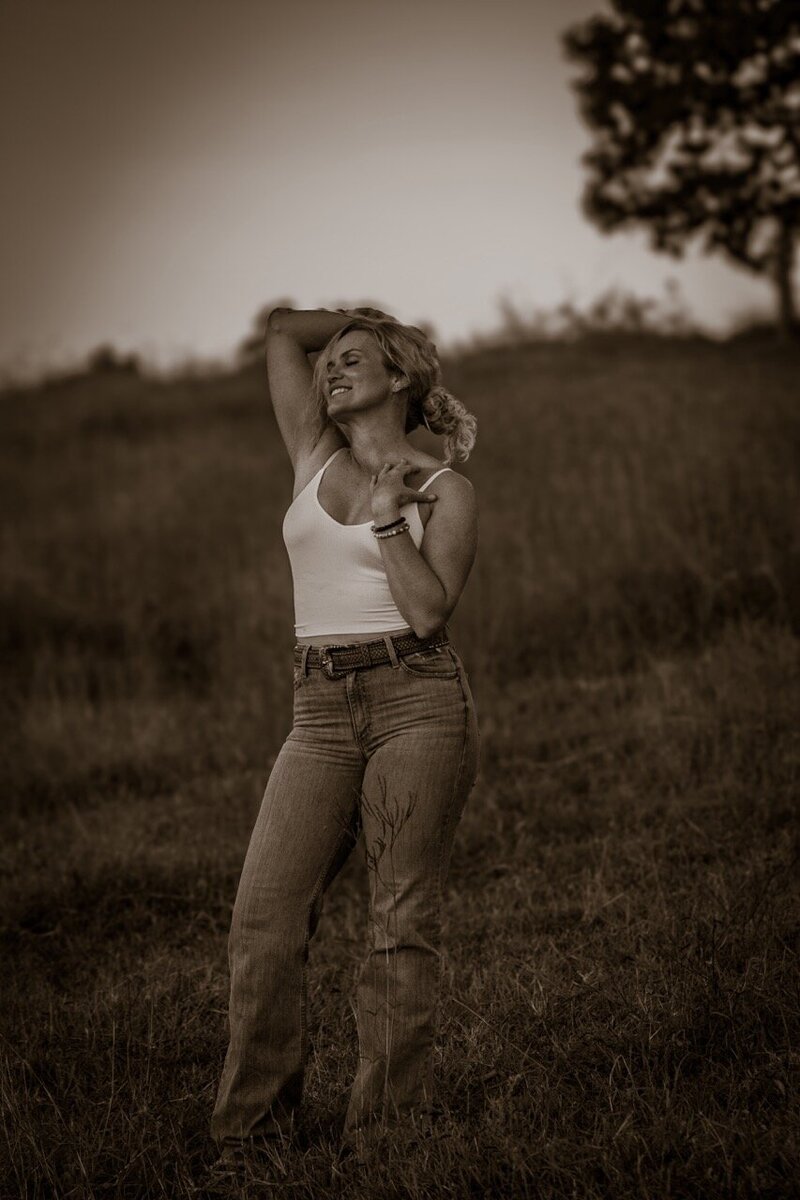 Woman standing in field embracing her beauty and her own Goddess Within.