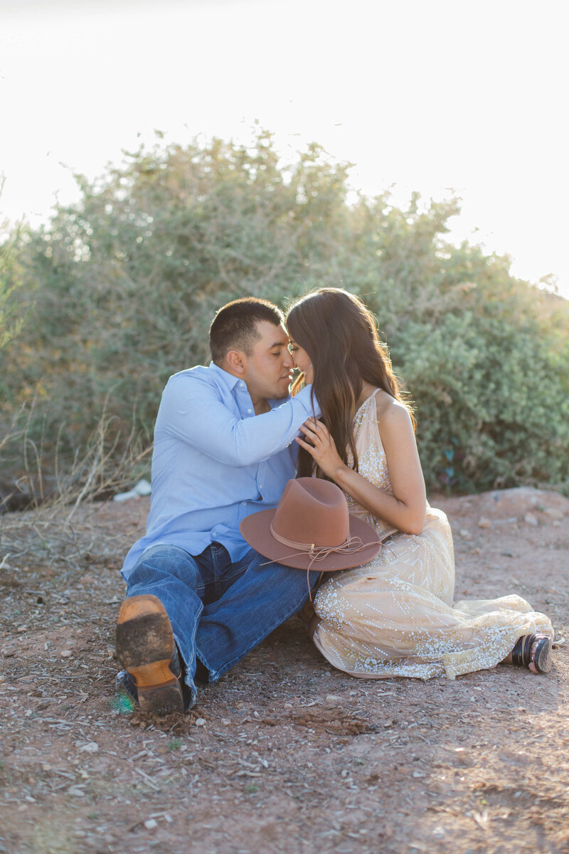 couple sitting on ground kissing during engagement session