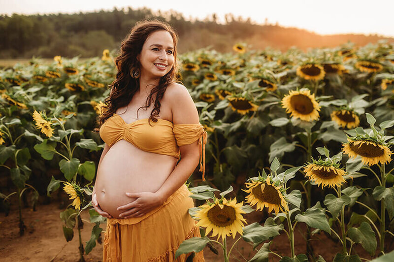 Pregnant mother poses in a sunflower field for Maternity Photoshoot in Asheville.