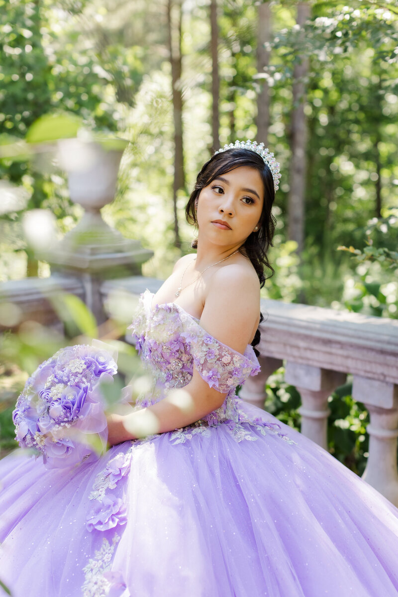 woman wearing purple quinceanera dress and holding bouquet of purple flowers