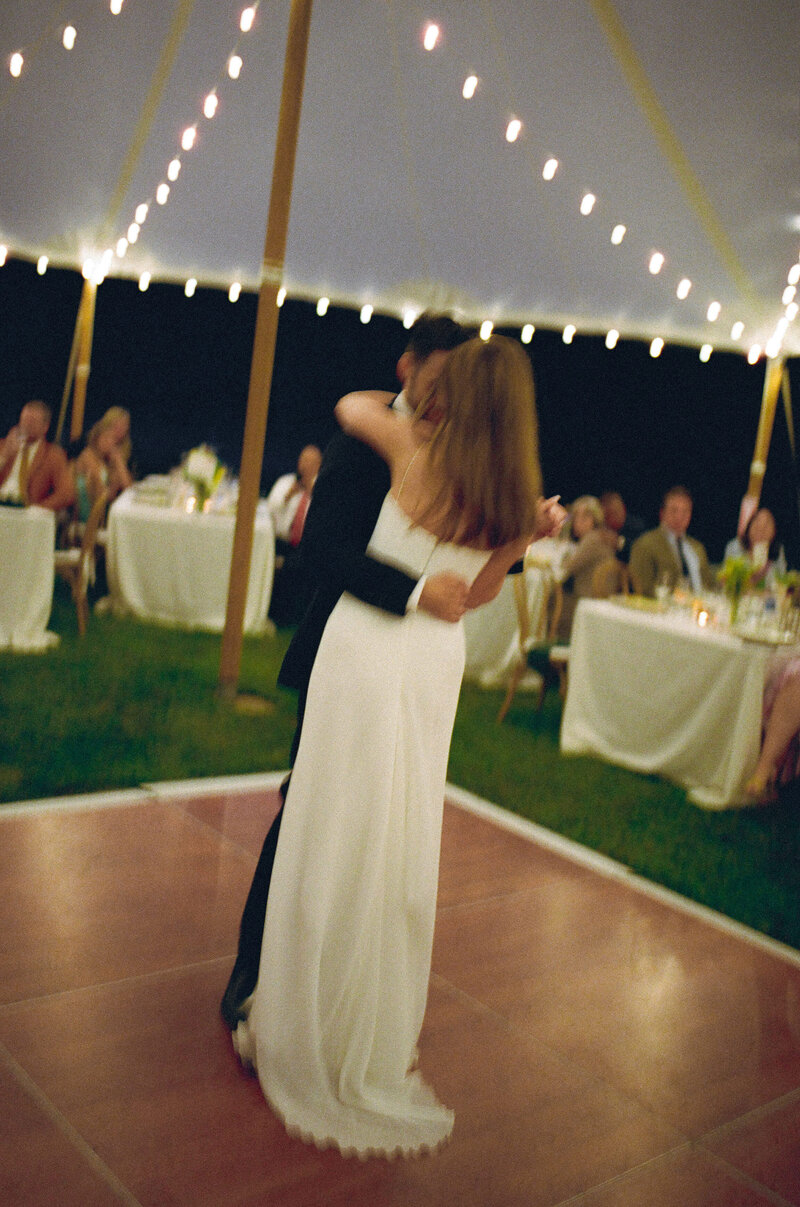 Intimate Brooklyn wedding couple sharing their first dance under string lights at an outdoor tented reception