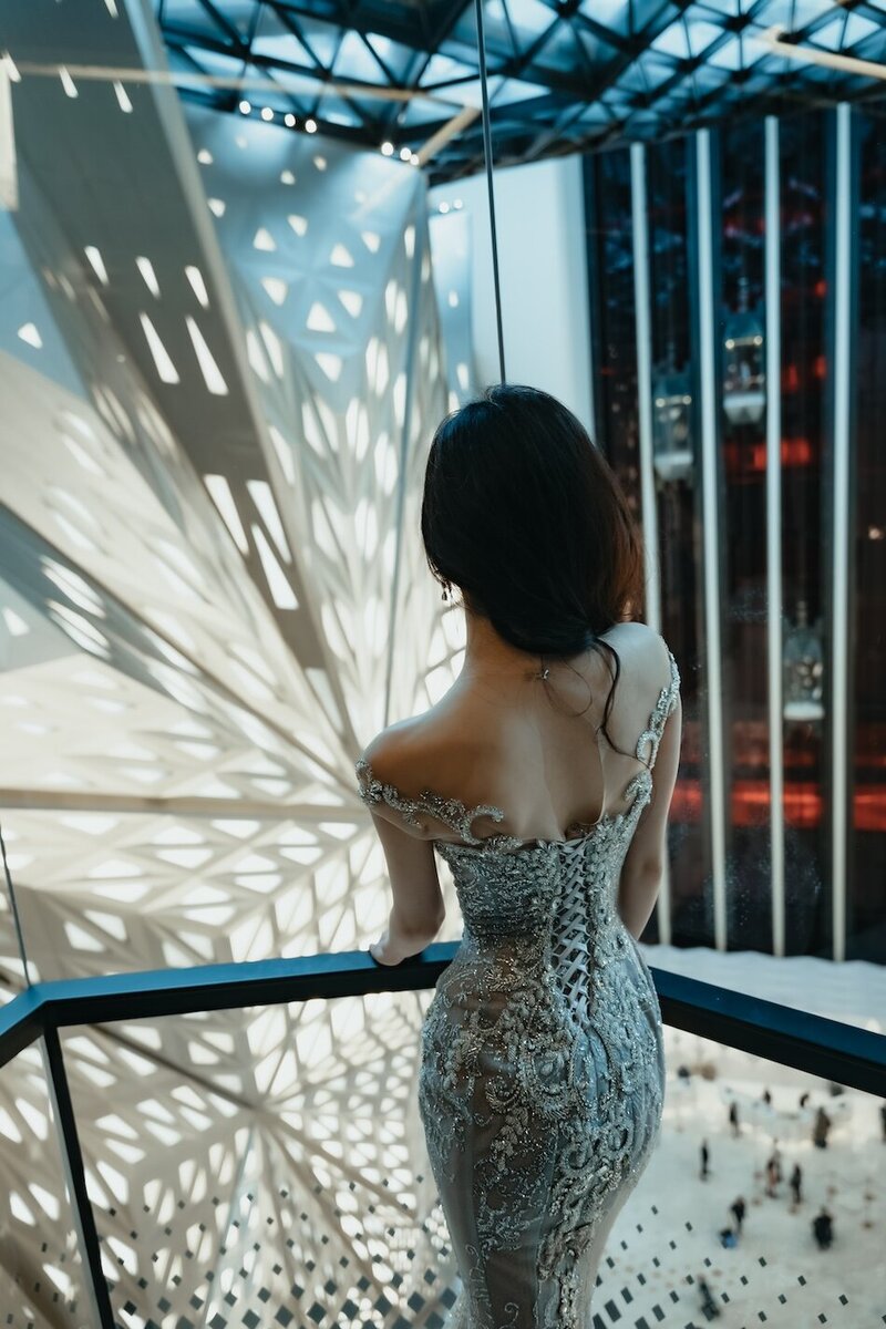 A woman in an abstract geometric lit room wearing a stunning couture dress.