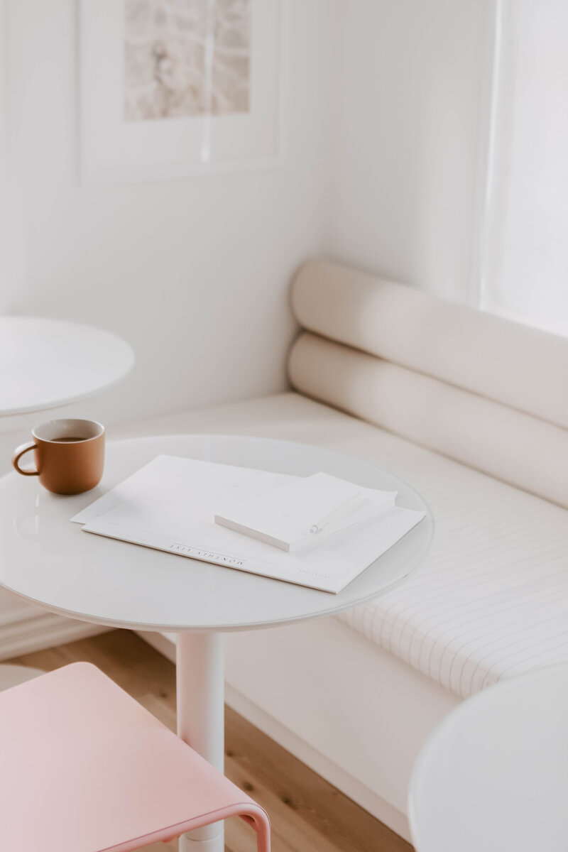 coffee mug on white table with white notebooks