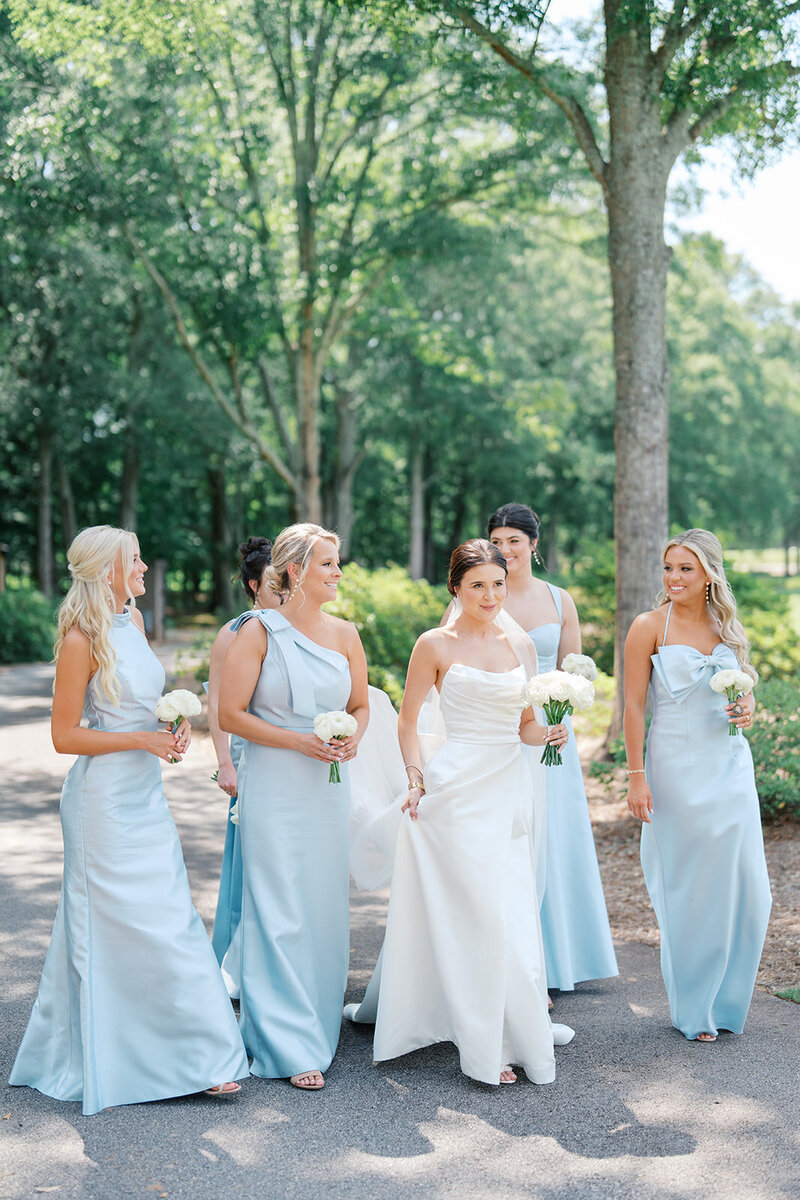 bride walks holding bouquet with bridesmaids in blue dresses at georgia vineyard wedding