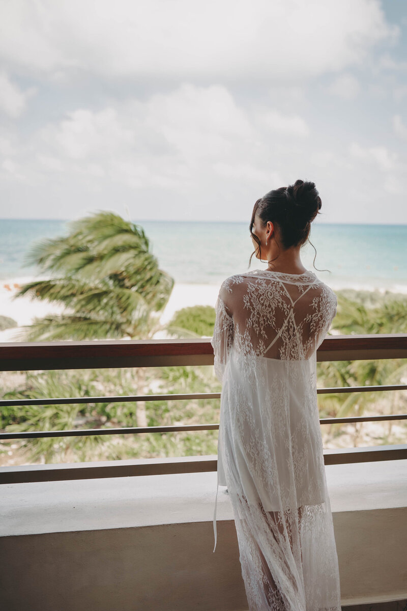 bride standing on balcony looking out at the ocean