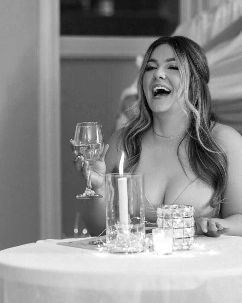 Woman laughing at a candlelit table, enjoying a festive event.