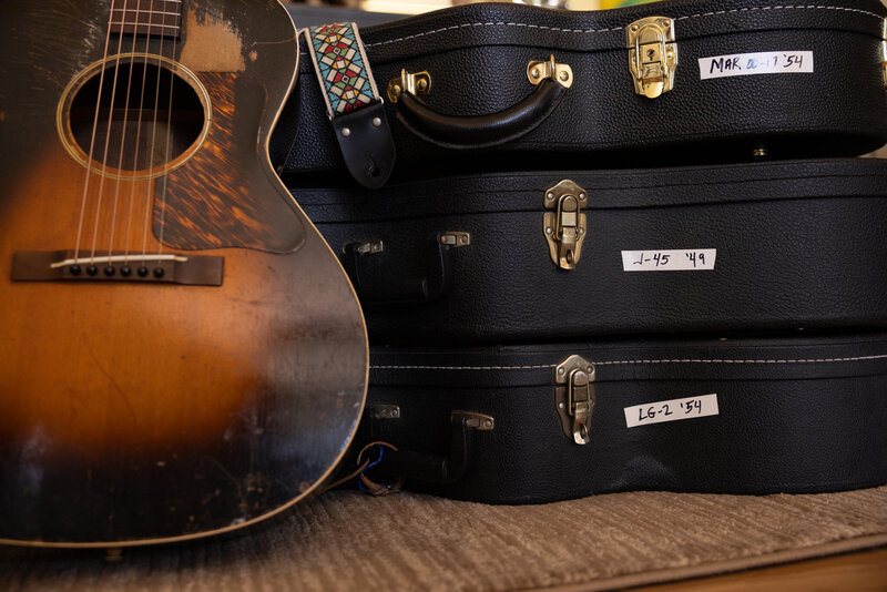 Acoustic Guitar with a stack of guitar cases.