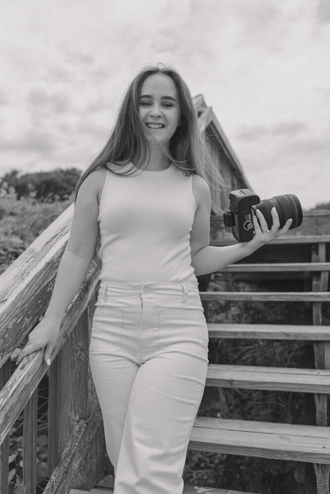 Photographer walks and smiles while holding camera