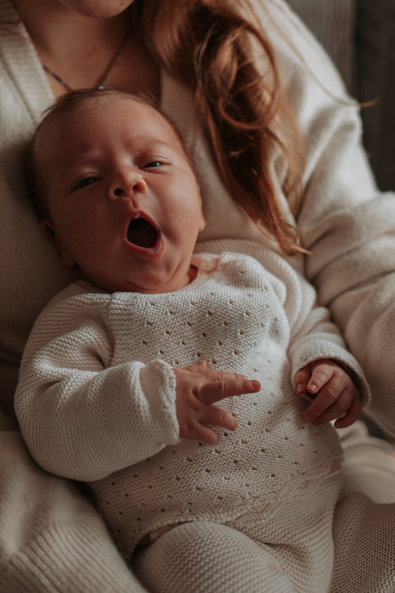 Een vrouw met een gapende baby in haar armen
