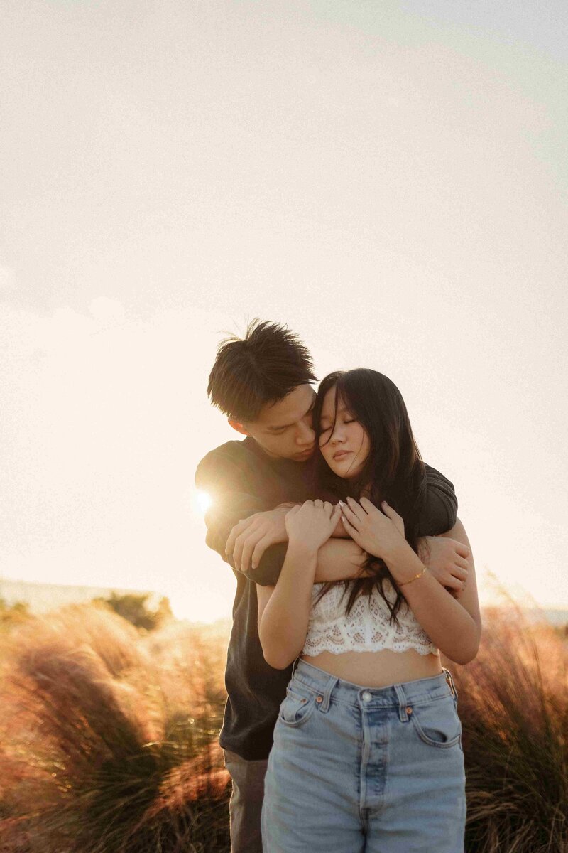 couples hugging each other in a golden hour background and some grass