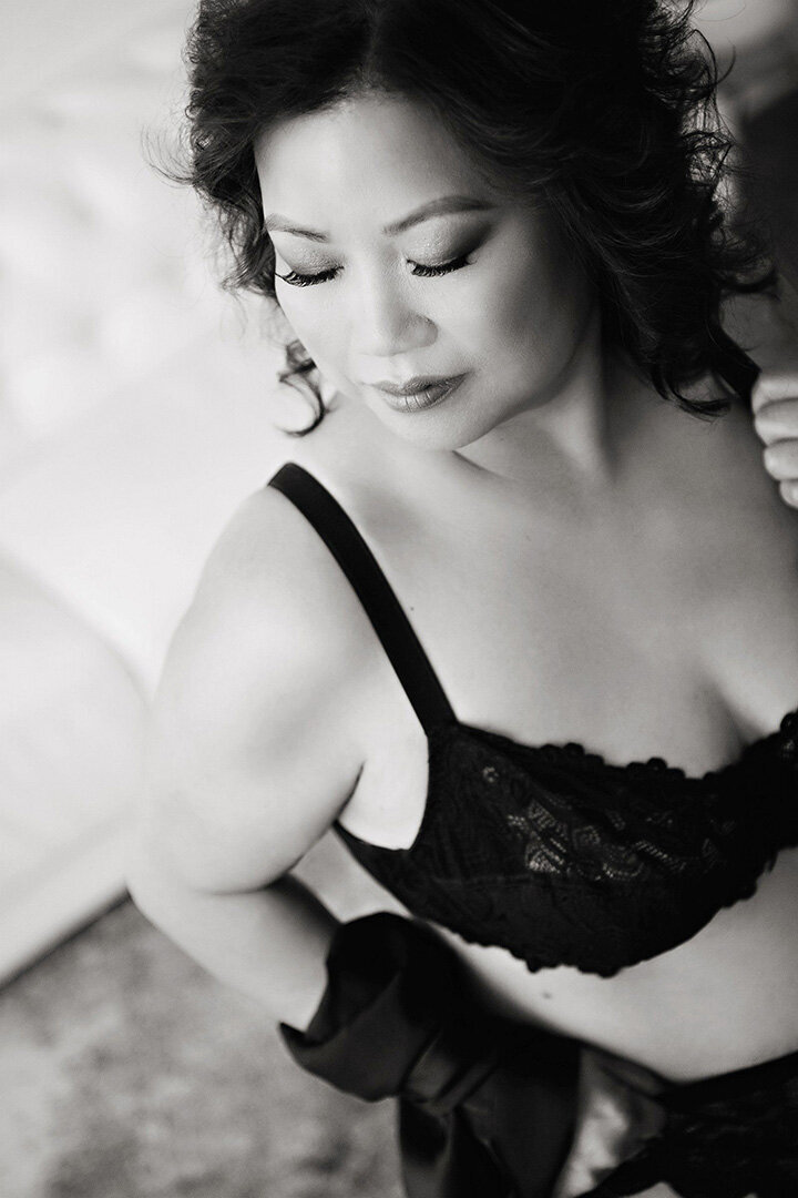 Darkly lit boudoir portrait of androgynous woman in white tank top