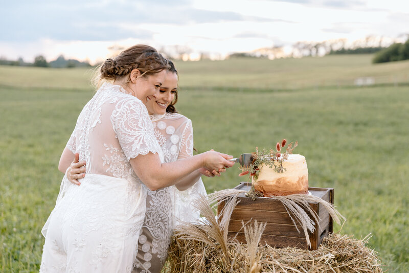 Two brides cutting a cake during their elopement.