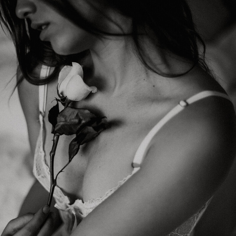 A black and white image of a woman during a boudoir photoshoot in Las Vegas holding a rose to her chest.