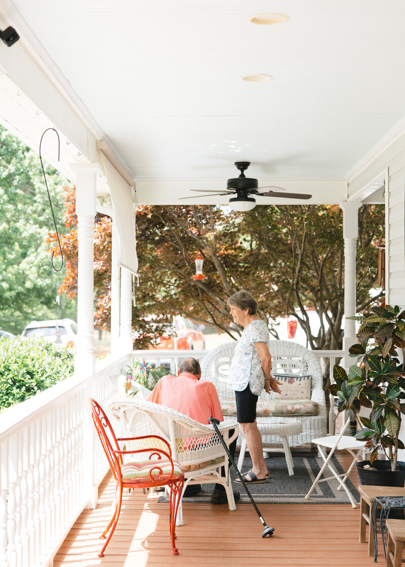 Grandparents on their porch surrounded by trees and plants