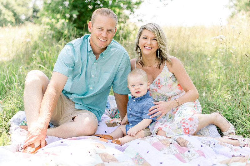 parents sitting on a picnic blanket with their baby