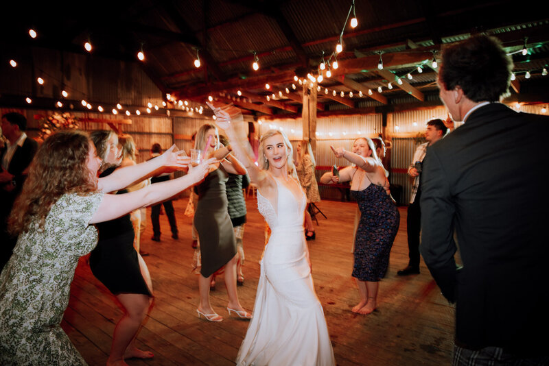 Bride dancing on the dancefloor in the middle of a circle of friends