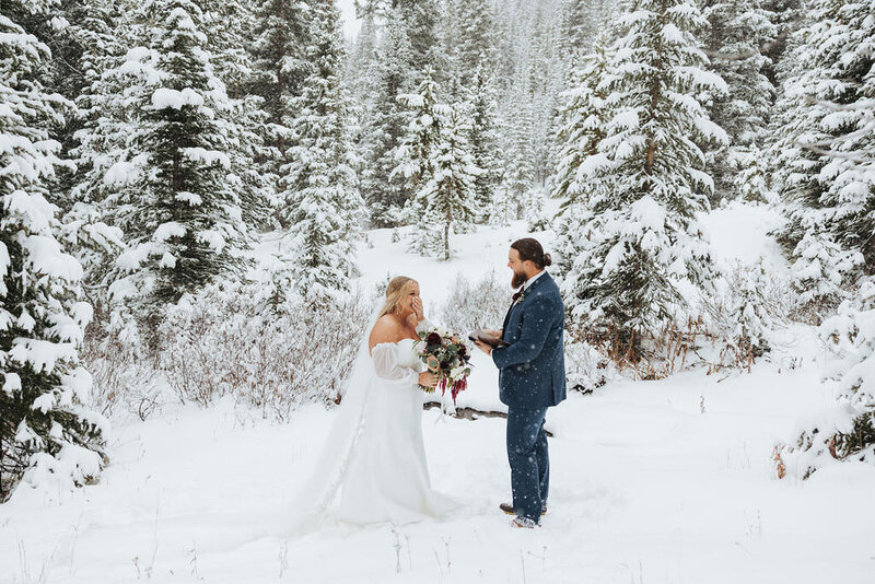 couple having a wedding ceremony in snow covered mountains