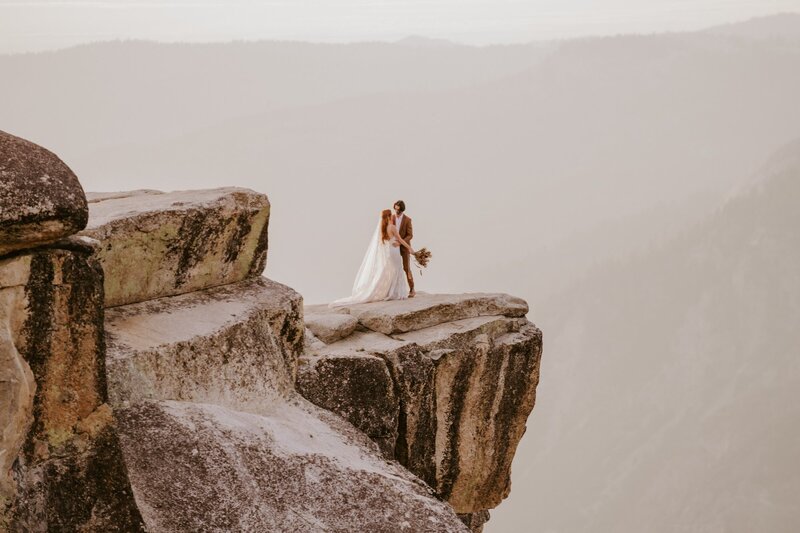 Couple kiss at Taft Point during Yosemite elopement at sunset