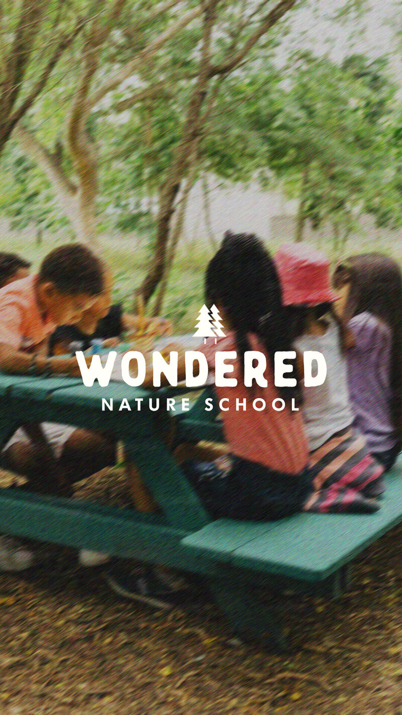 A group of children enjoying a picnic outdoors, with Wondered’s primary logo overlaying the image, reflecting the brand's connection to creativity and community.