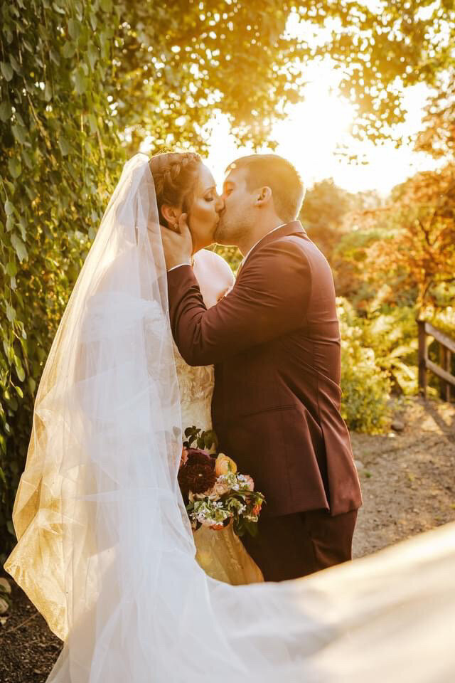 bride and groom posed during golden hour with her custom pearl bridal veil