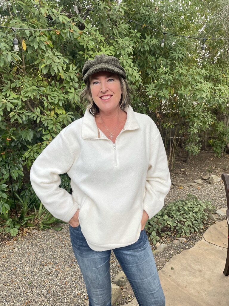 Laura Kate McHugh standing with hand on hip and driving hat, embodying direction, support, and the empowered path to self-discovery