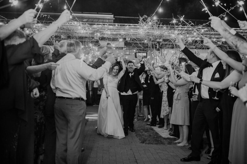 A newlywed couple exiting in a tunnel of guests holding sparklers