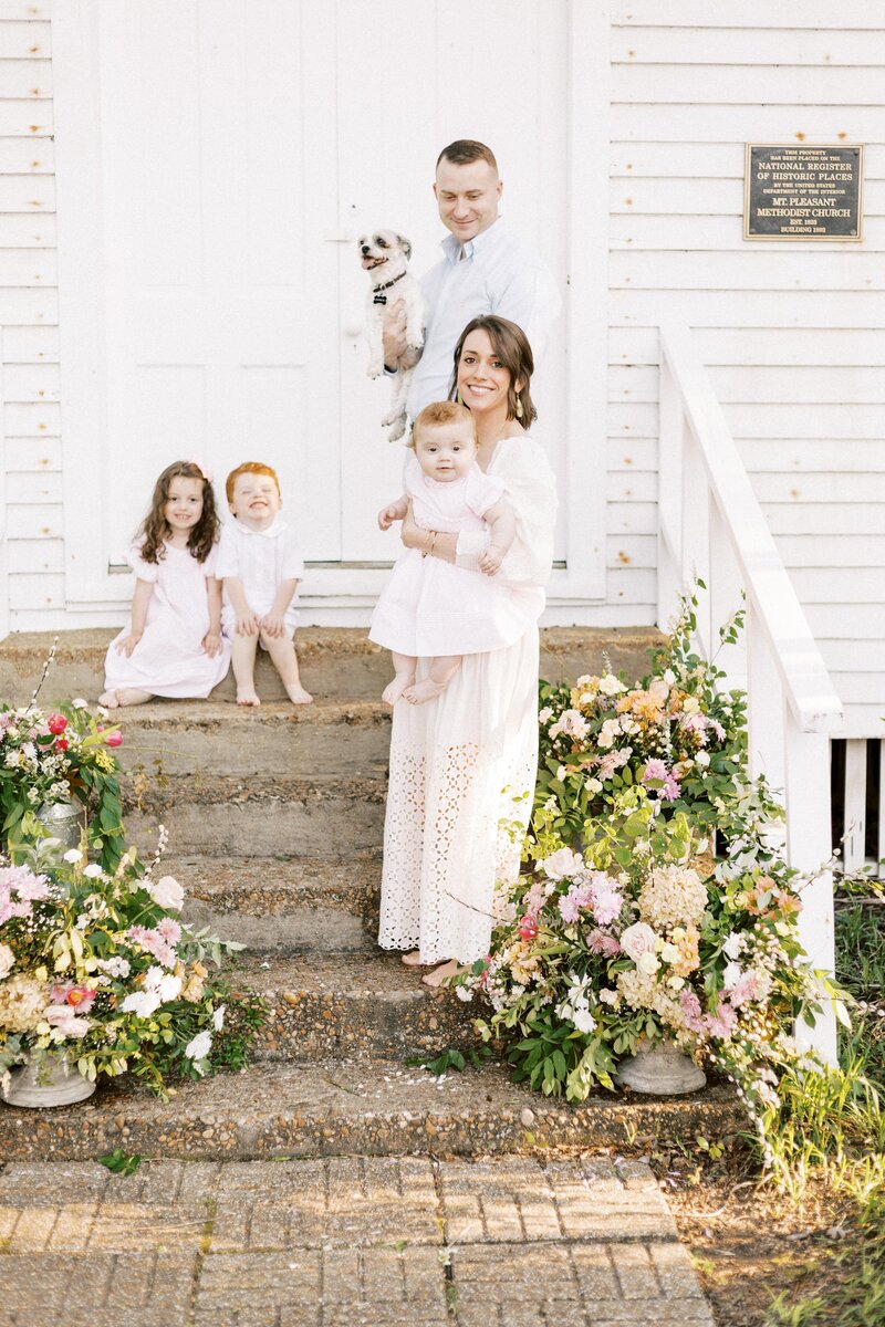 mom standing on steps holding baby with family behind her in peoria, illinois family photos 
