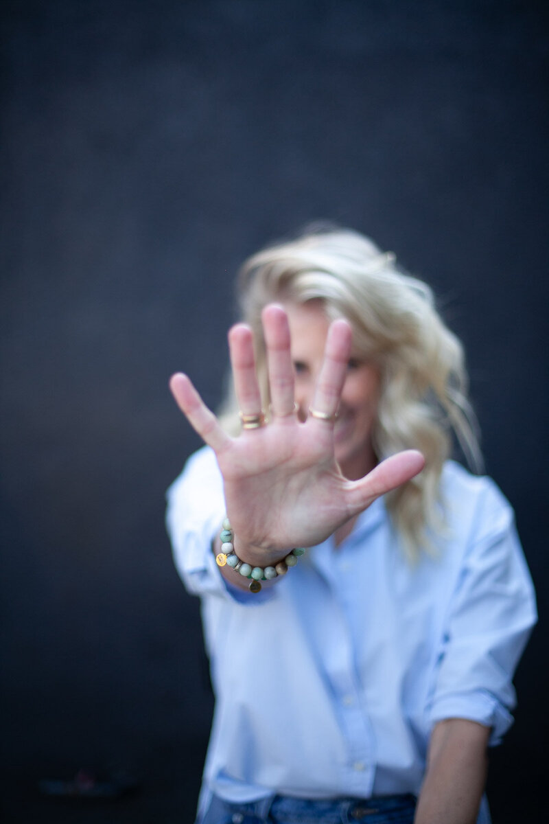 Stephanie, the best portland realtor for family's, holds her palm up at the camera with the rest of her out of focus. 