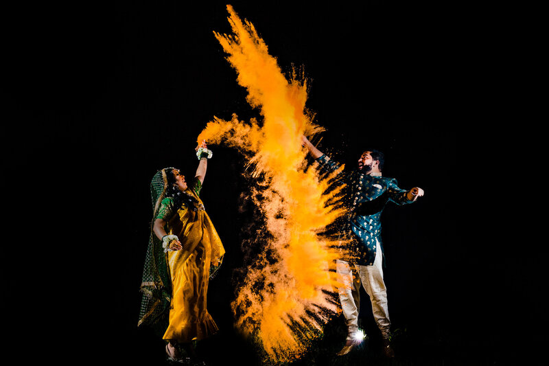 A wedding couple throwing an orange color bomb in the air as they jump for joy at the end of their wedding night in Toledo Ohio