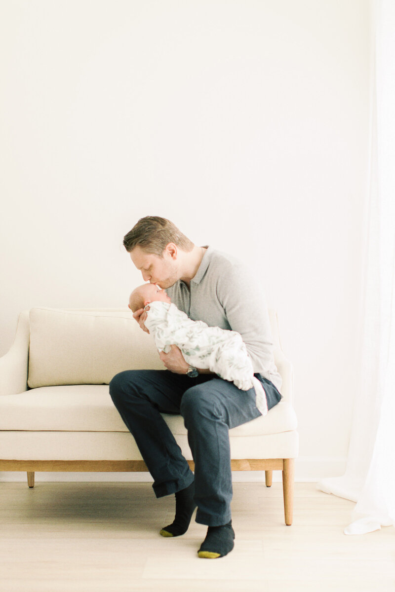 dad kissing swaddled baby by Chicago Newborn Photographer