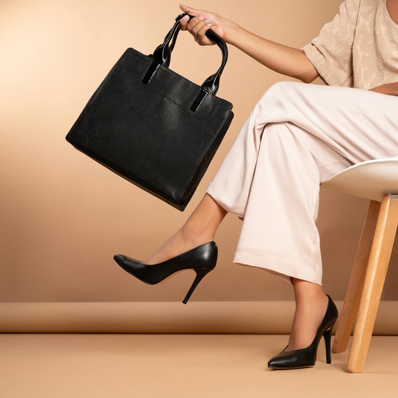 Confident professional woman in heels holding a black handbag, symbolizing empowerment and poise