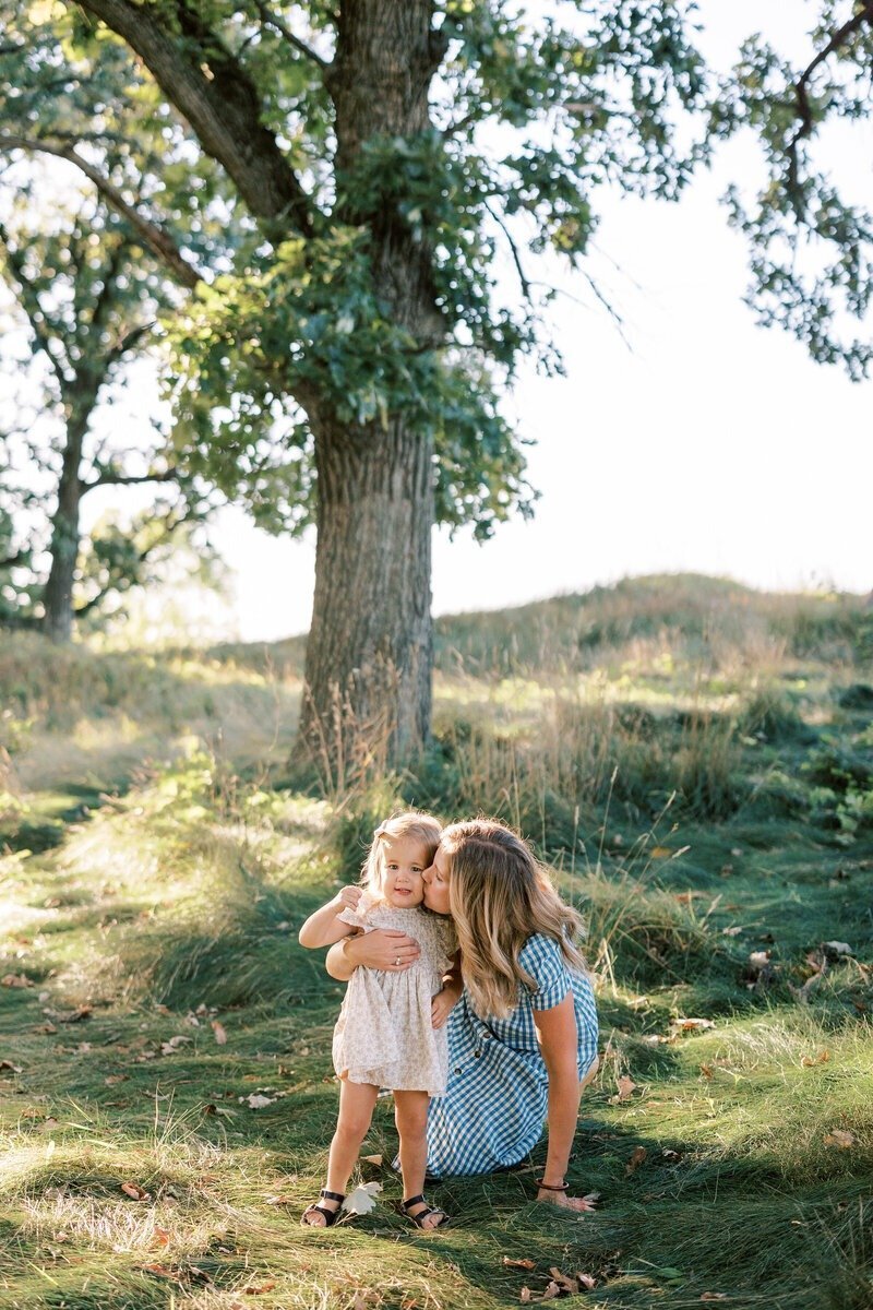 A loving portrait of a mom kissing her daughter, captured by Emily Barbara, family photographer in Milwaukee.