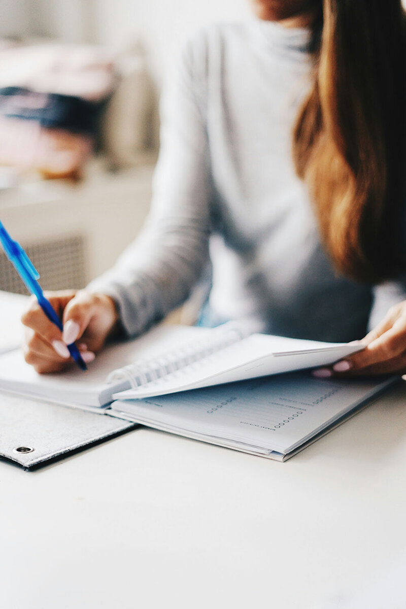 Stock photo of hands writing in a spiral-bound notebook or planner. 