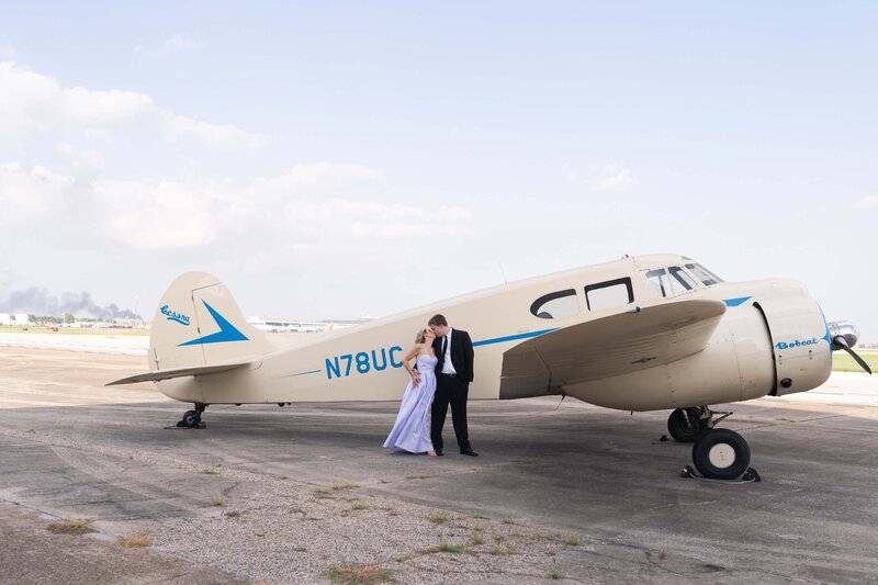 engaged couple kiss in front of an old air plane at 1940 Air Terminal Museum groom kisses bride to be on a rooftop in downtown Houston by Swish and Click Photography