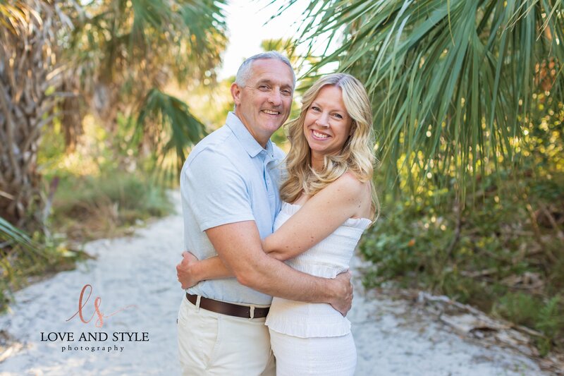 Couple celebrating their 40th anniversary hugging and smiling with Siesta Key Beach path as the background