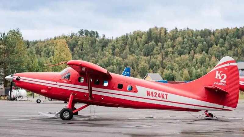 A red and white ski plane sits, awaiting guests on the tarmac at the local air hub.  This plane takes eloping couples and their guests to  glacier landing elopement in Denali National Park as part of their adventure luxe Alaska elopement package. 