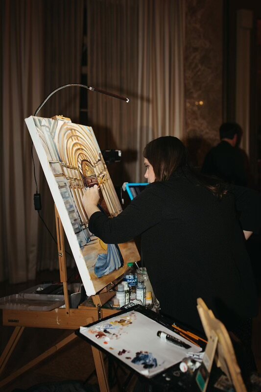 A behind the scenes style photo of Debbie completing a live wedding painting