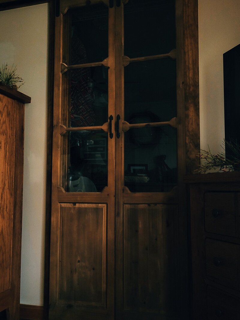 Antique glass and wooden skinny doors that slide apart to open up into walk in closet in bedroom
