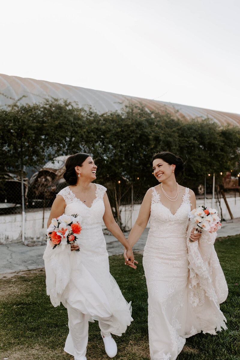 A newlywed couple holding hands and smiling at each other 