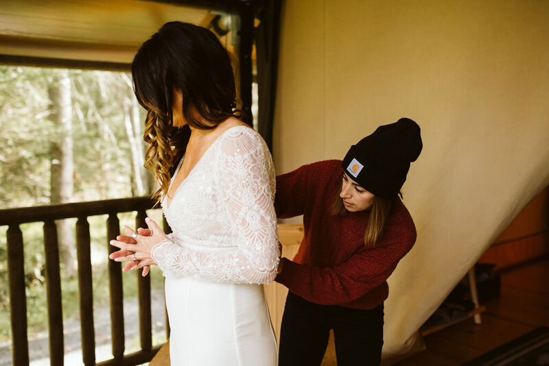 Leavenworth wedding planner helping bride zip up dress outside of glamping tent.